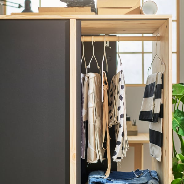 Armoire GLAMBERGET vue de côté avec les portes coulissantes ouvertes des deux côtés, pour montrer les vêtements suspendus et pliés à l'intérieur.