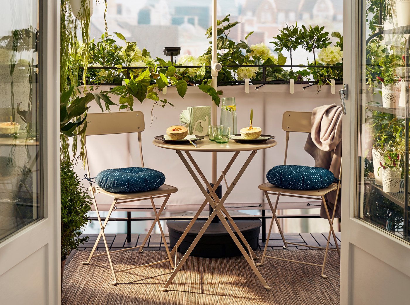 Een klein balkon met een tuinset en een parasol die zorgt voor wat beschutting.