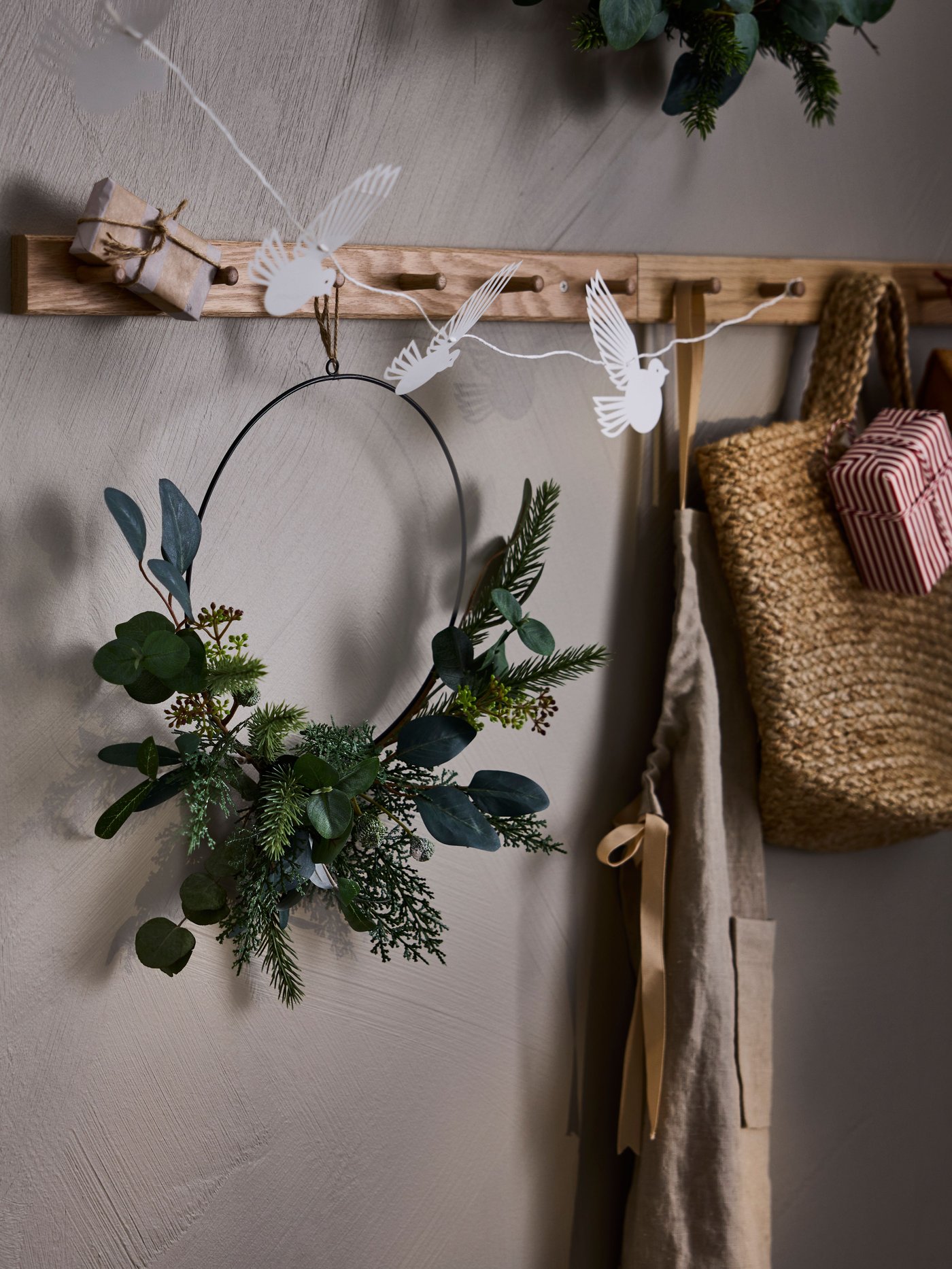 Una corona navideña VINTERFINT verde colgada en un perchero IKEA. 