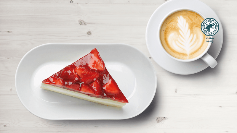 Erdbeerdreieck mit Cappucino auf einem Tisch präsentiert.