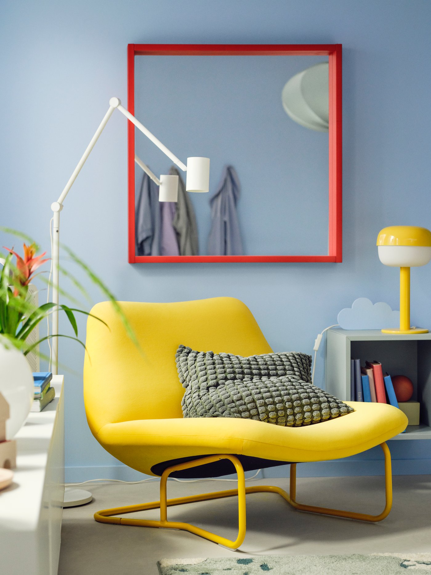 Living room featuring a square TURBOKASTANJ mirror with red frame, placed above a yellow SOTENÄS armchair.