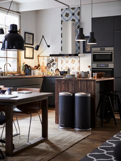 Kitchen with a grey base cabinet with three drawers, a wall mounted extractor hood, a table with a brown chair, and a rug.