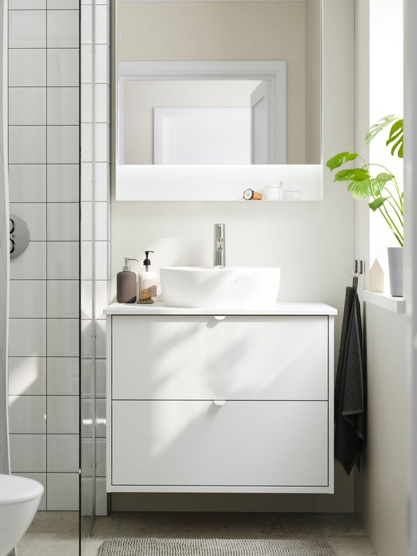 A bright bathroom has a shower, a HAVBÄCK wash-stand with drawers, a TÖRNVIKEN countertop wash-basin and a FAXÄLVEN mirror.