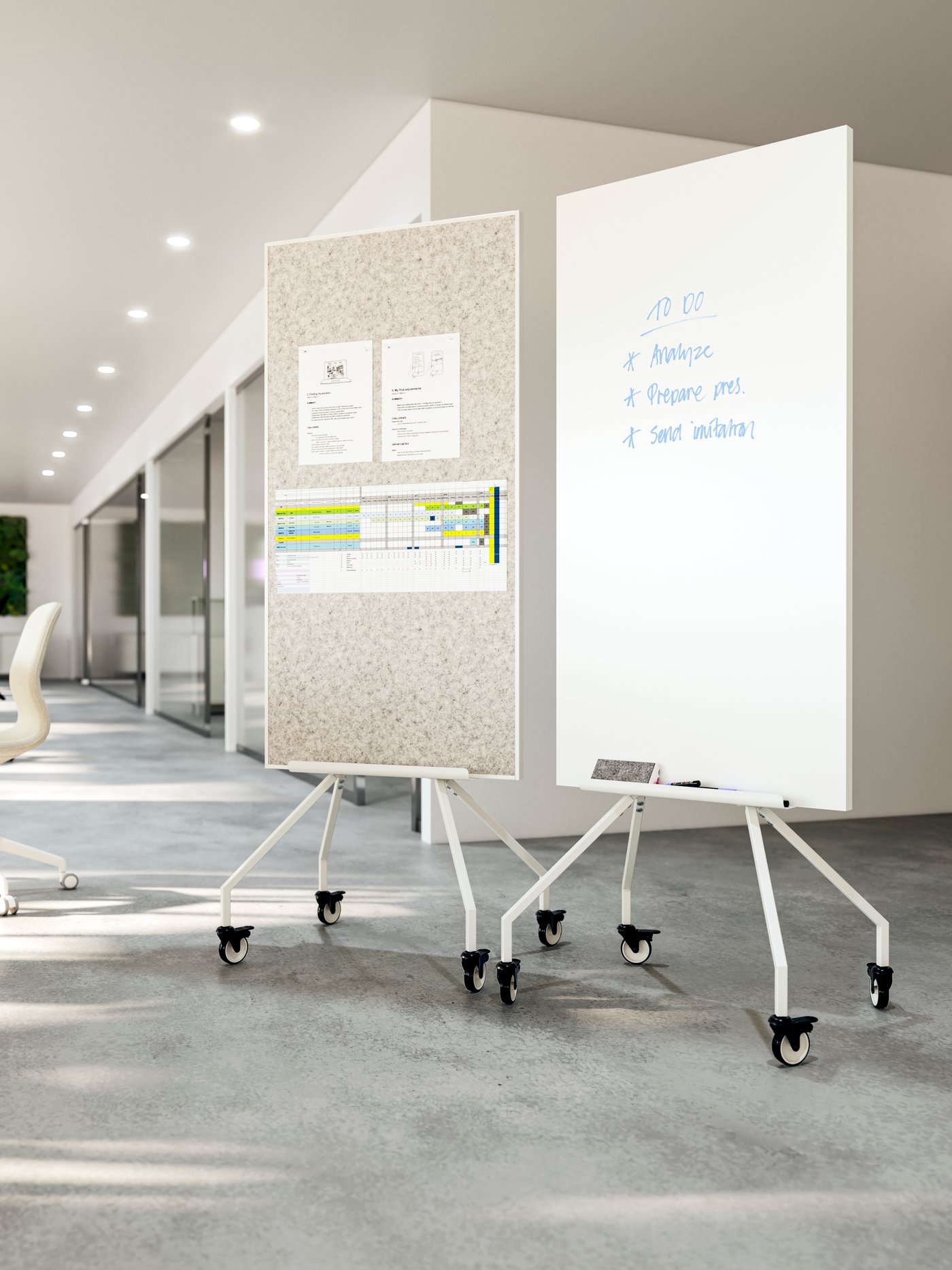 Two ELLOVEN whiteboards/noticeboards on wheels standing next to each other in an airy office.