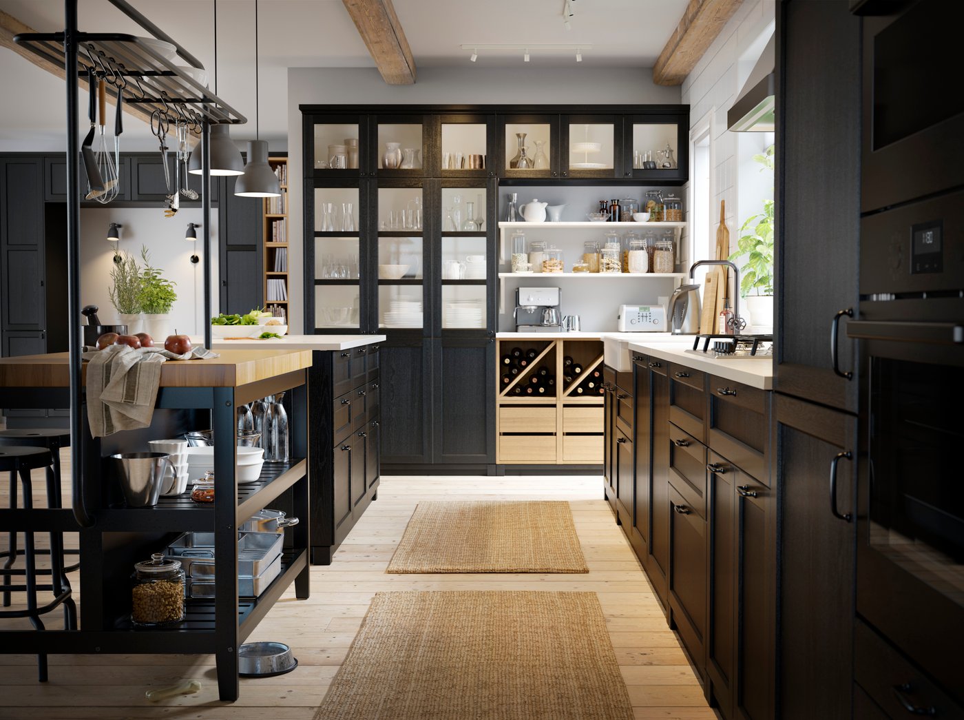 Una cucina nera con pavimento in parquet, un'isola nera, mobili neri e bottiglie di vino conservate in un elemento a giorno.