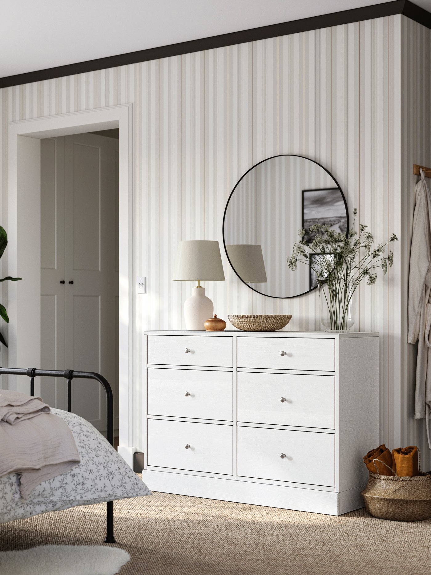 Bedroom with STJÄRNÖ bed frame, wallpaper in beige and white, a white HAVSTA chest of drawers with a round mirror above it.