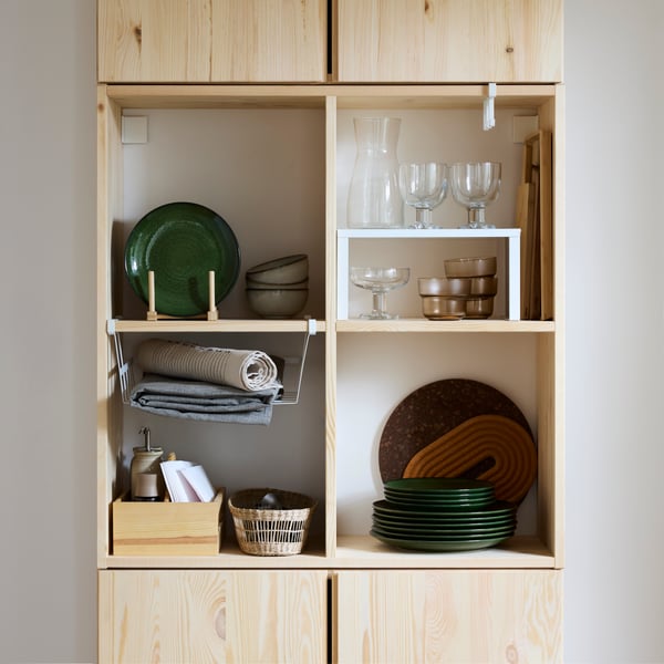 Many items, including VARIERA shelf inserts and plates, stand inside an IVAR shelving unit on top of an IVAR cabinet.