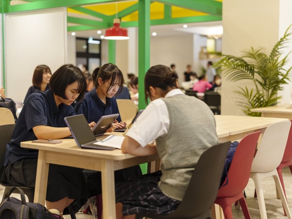 複数人がテーブルを囲んで作業するコラボレーションスペース。ノートPCや資料を使用中