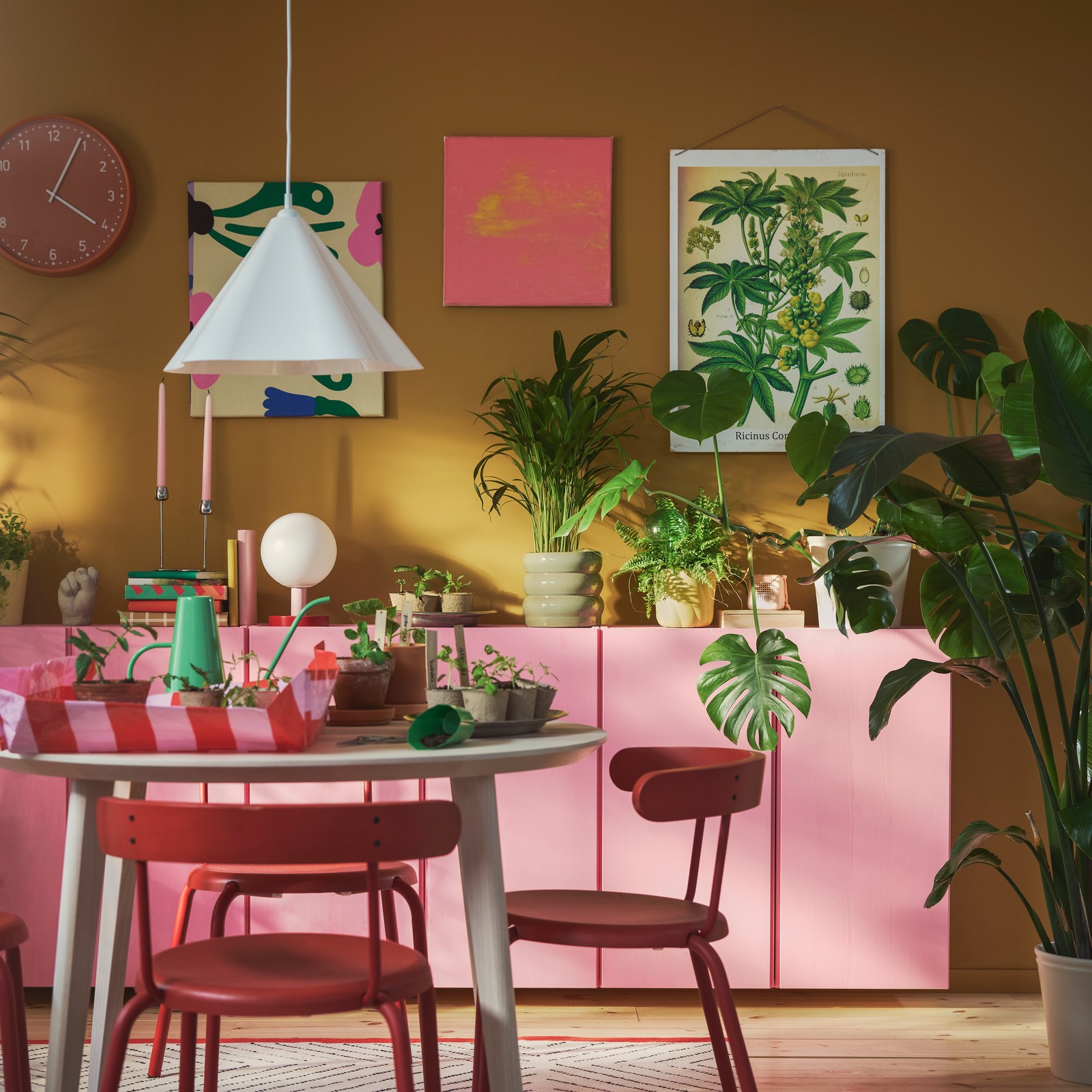 A colourful living room filled with green plants, and on a round table are DOFTRIPS growing items. Three red chairs.