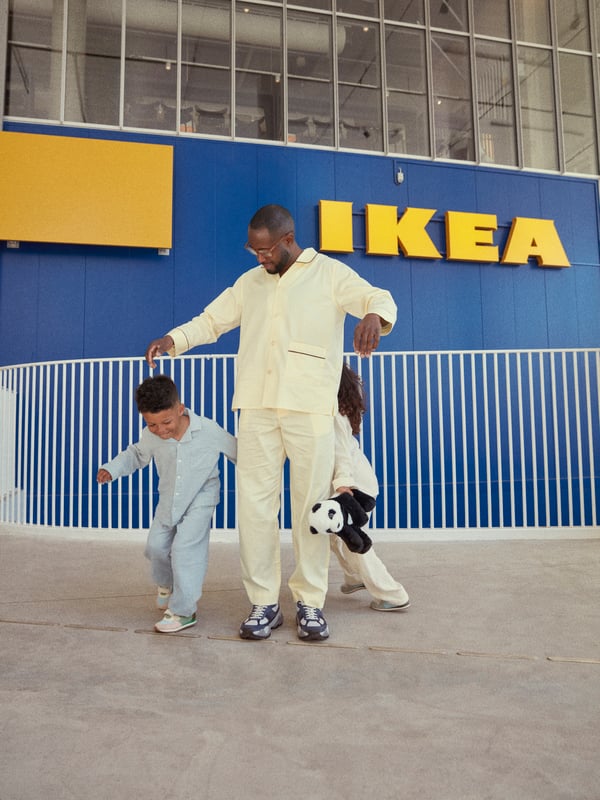 Father and two kids playing together in front of an ikea store 
