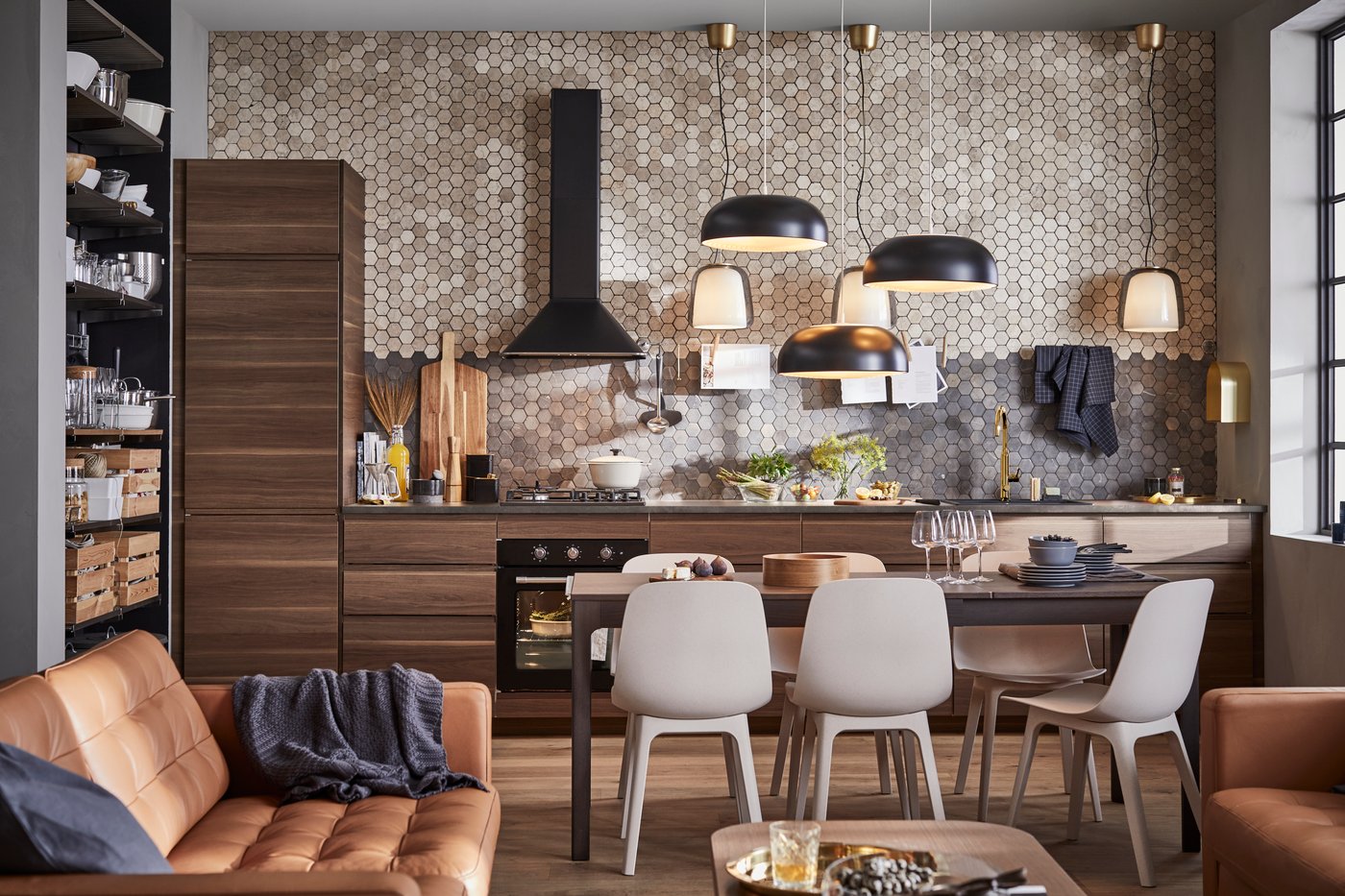 Una cucina con mobili in legno marrone scuro effetto noce, tre lampade a sospensione nere, un tavolo marrone scuro e sei sedie.
