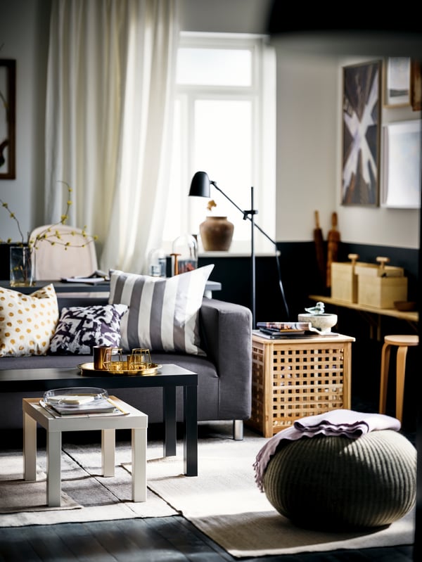 A room in a black-and-white colour scheme with black and white LACK nesting tables and a dark-grey KLIPPAN two-seat sofa.