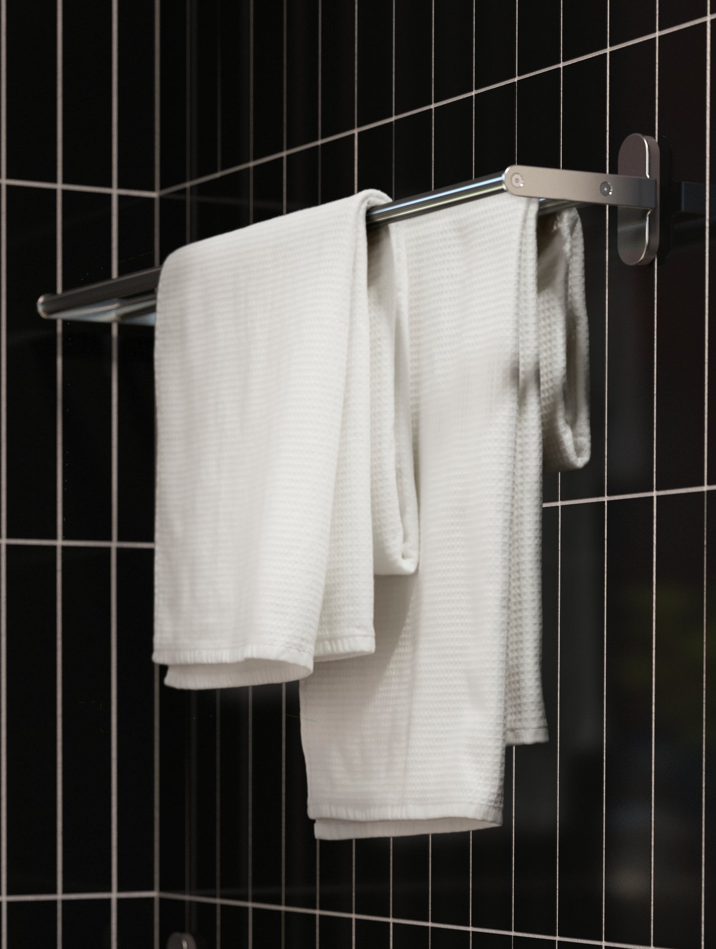 A BROGRUND towel rail mounted on a bathroom wall clad in narrow, black tiles. On the rail hangs two white towels.