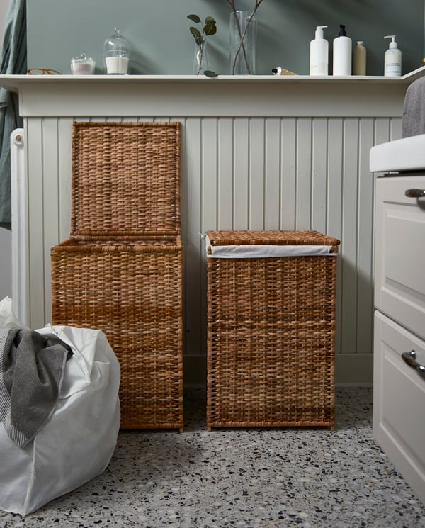 Two BRANÄS rattan laundry baskets with linings. One basket is open, and its lining with laundry inside stands next to it.