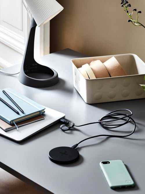 Desktop with a SVALLET work lamp, laptop with a LIVBOJ wireless charger linked to it, and office accessories.