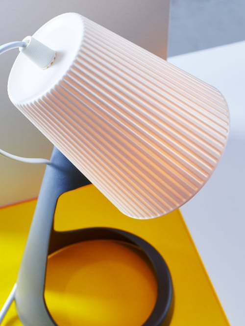 Lampe de travail SVALLET gris foncé et blanc sur présentoir jaune.