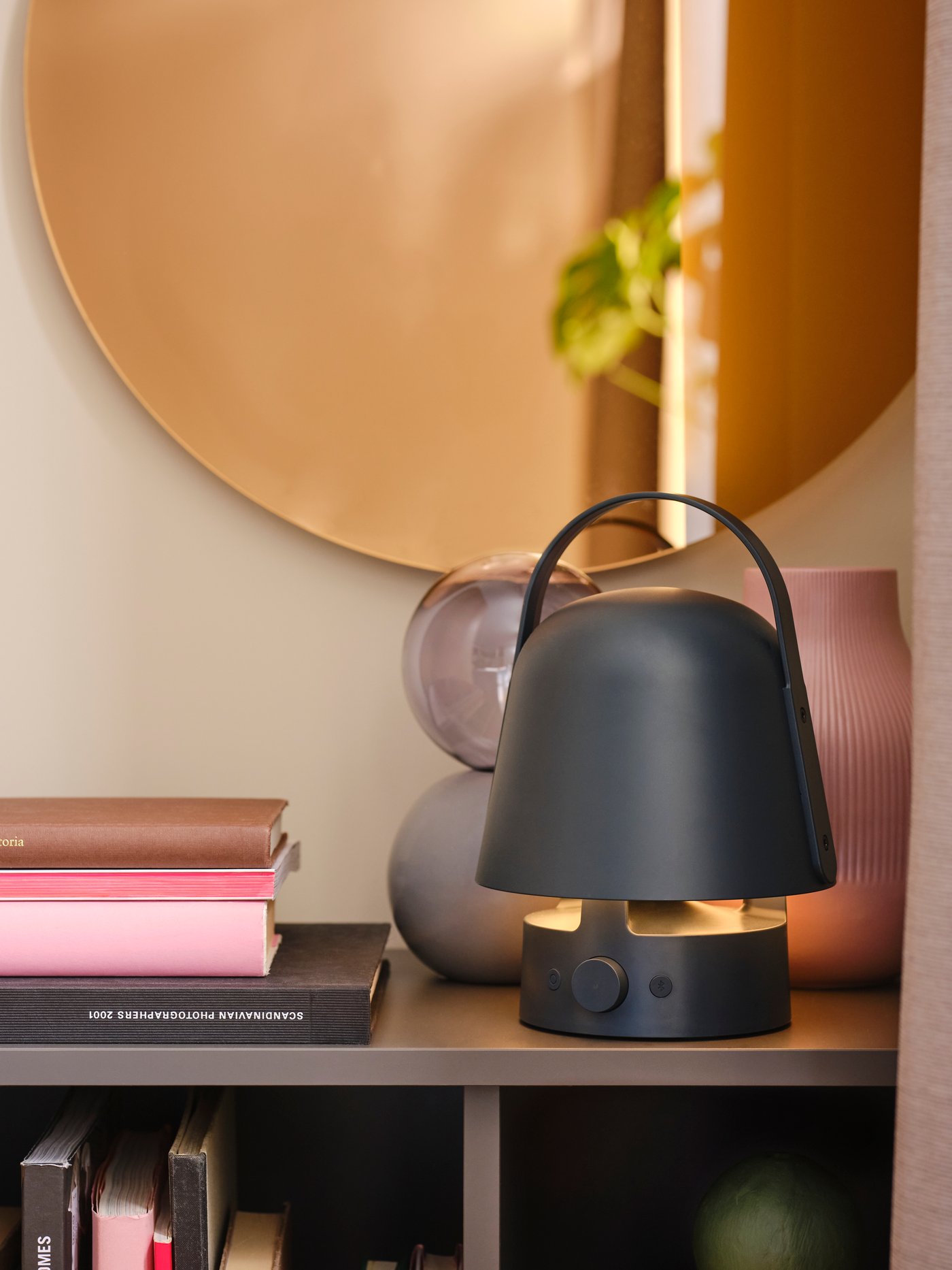 En VAPPEBY högtalare står uppe på en byrå med en rund spegel bakom.