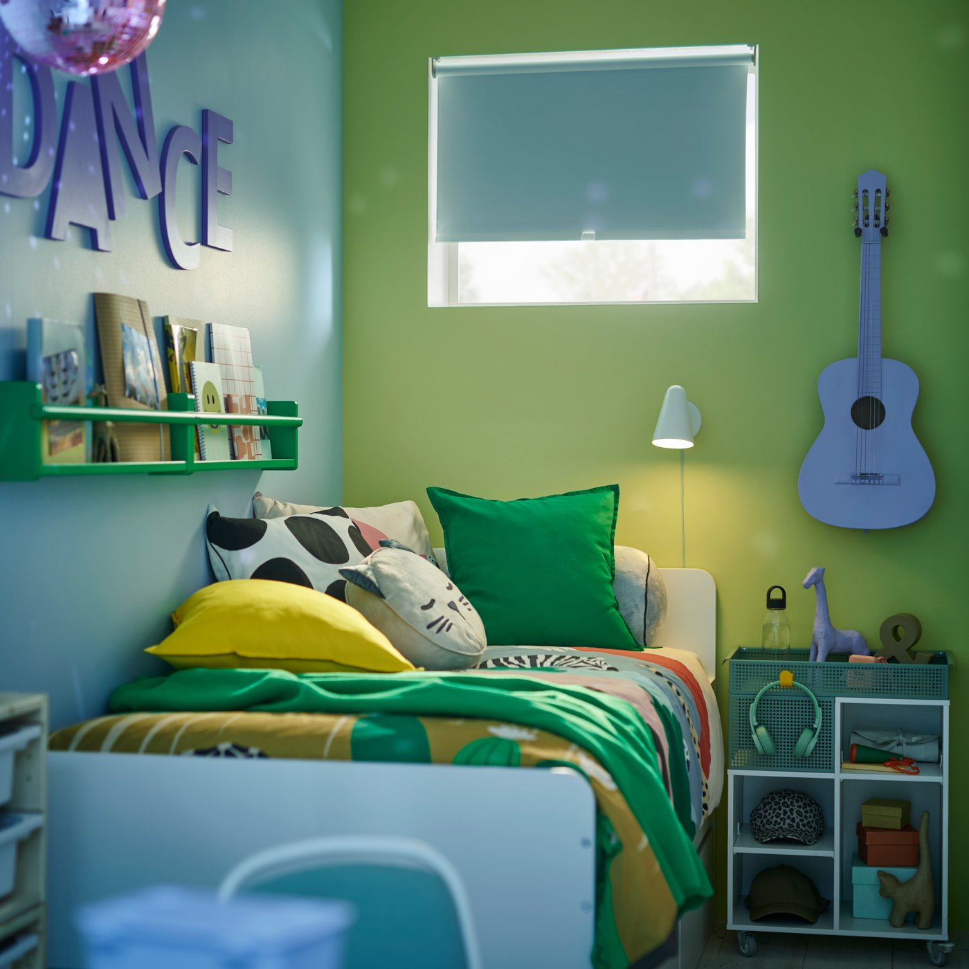 A white SLÄKT bed in a child’s bedroom that has green and blue walls covered with cushions in green and yellow GURLI covers.