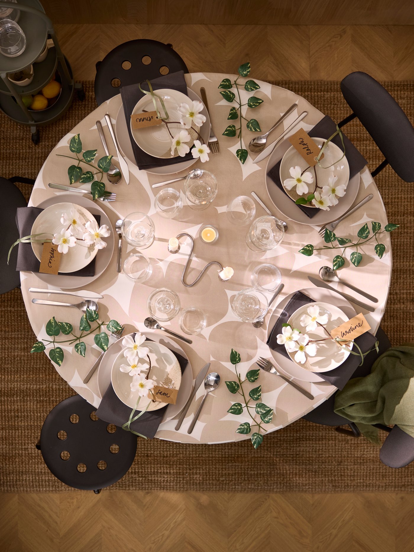 A round DOCKSTA table with a festive setting, including FÖRNUFT cutlery, KRUSTISTEL and FÄRGKLAR plates and leafy decoration.