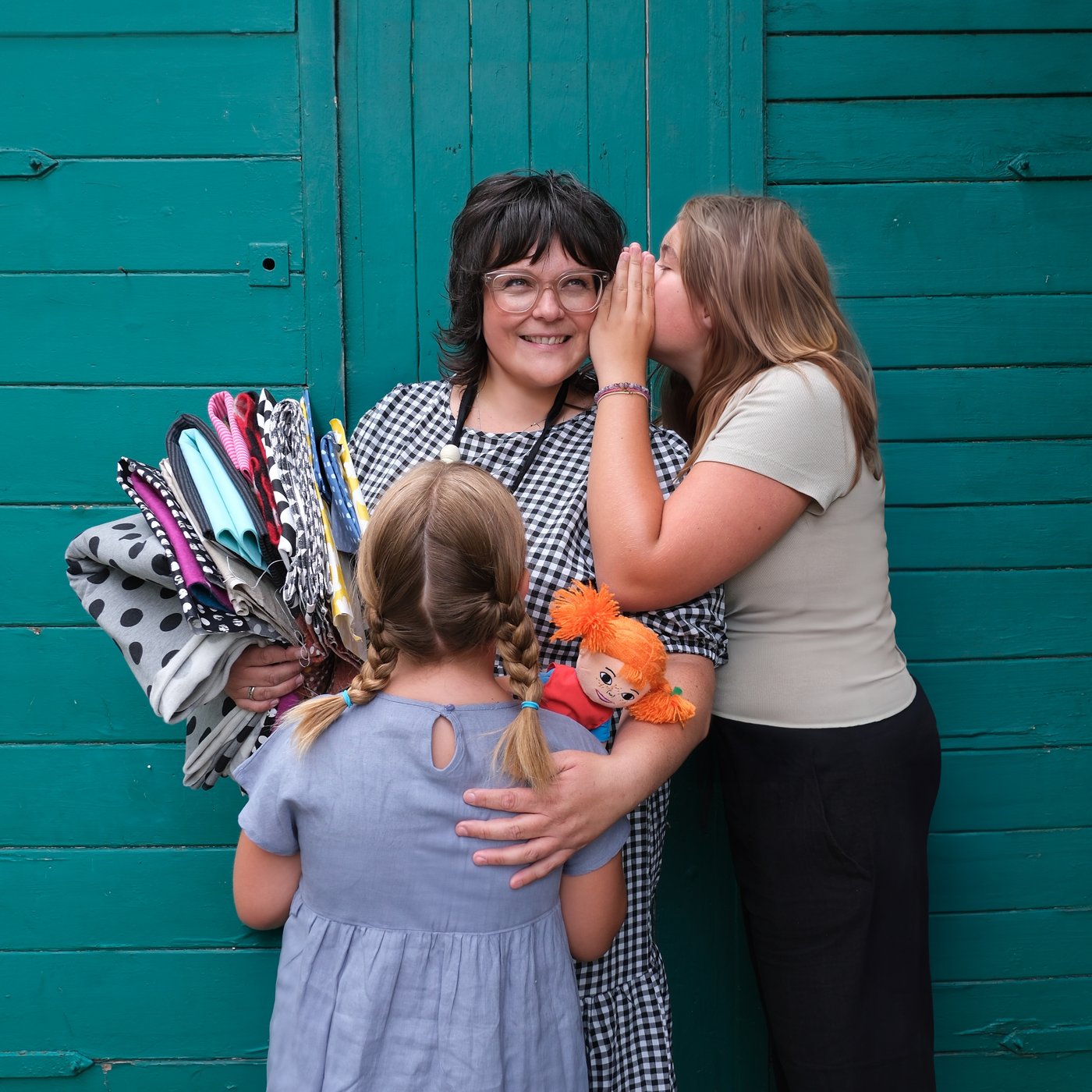 Zwei Frauen und ein Mädchen unterhalten sich vor einer grünen Wand