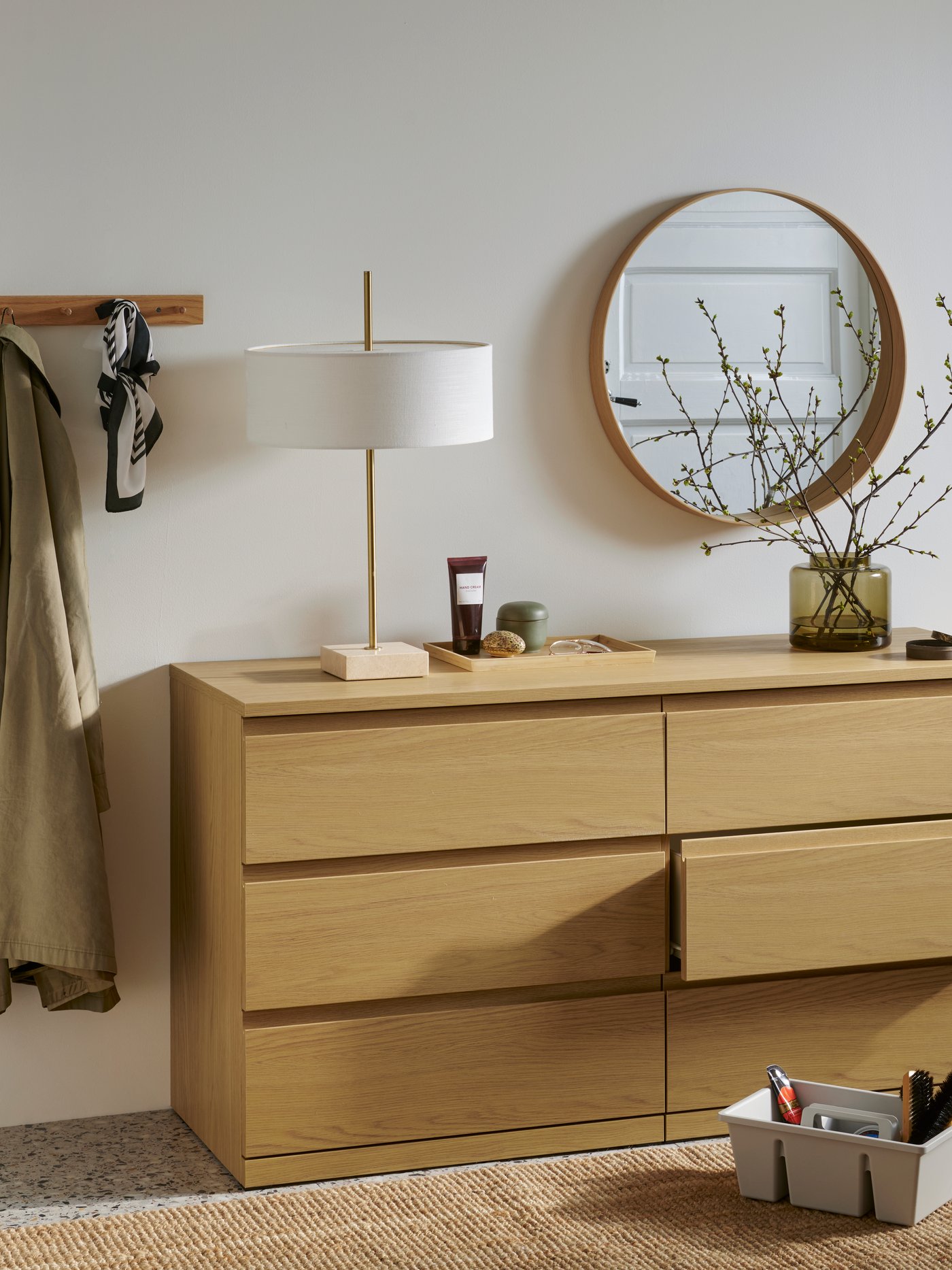 En STORKLINTA byrå med sex lådor i ekimitation, med en lampa och andra föremål ovanpå samt skovårdsprodukter på golvet.