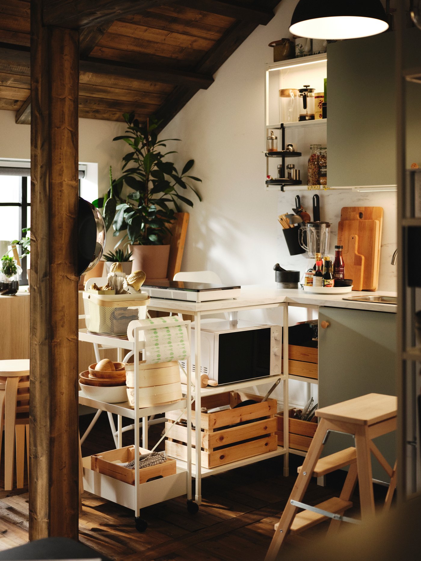 Bílo-světle šedozelená kuchyně ENHET s bukovými schůdky BEKVÄM a bílým vozíkem NISSAFORS.