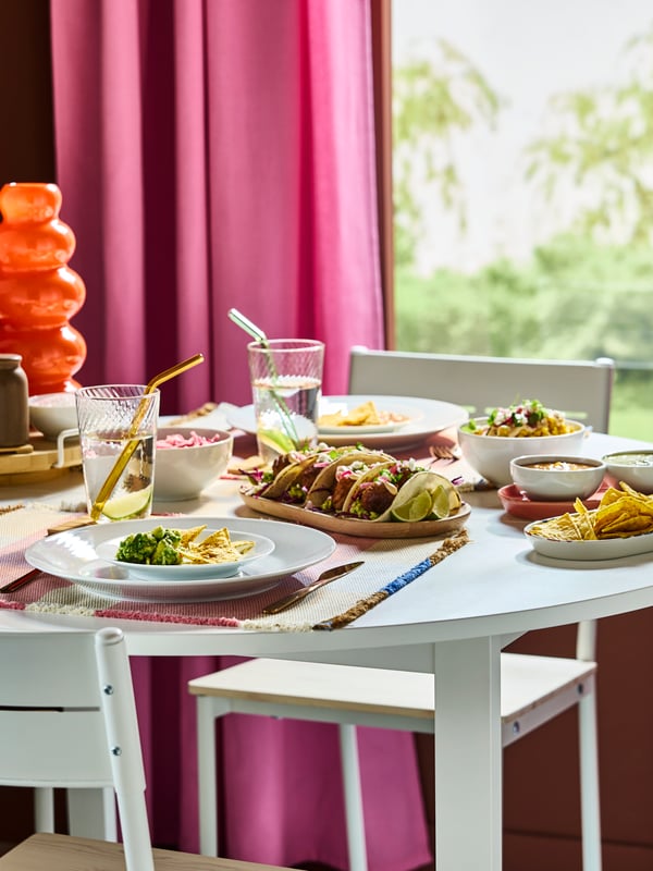 Festin mexicain sur une table ronde blanche VIHALS avec des assiettes blanches IKEA 365+ et des verres transparents KLIPPLAX à effet ondulé.