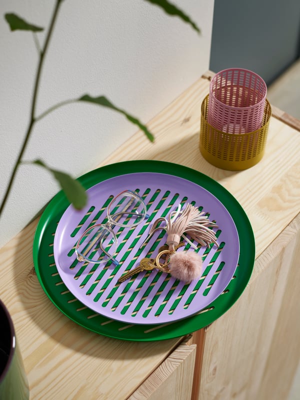 Two TESAMMANS trays stacked on top of each other holding a keychain and a pair of glasses, next to stacked tealight holders.