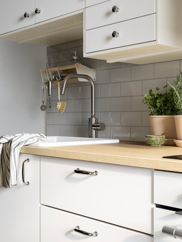 A METOD kitchen with white VEDDINGE fronts, chrome plated ENERYDA handles and knobs, an ash effect/laminate EKBACKEN worktop.