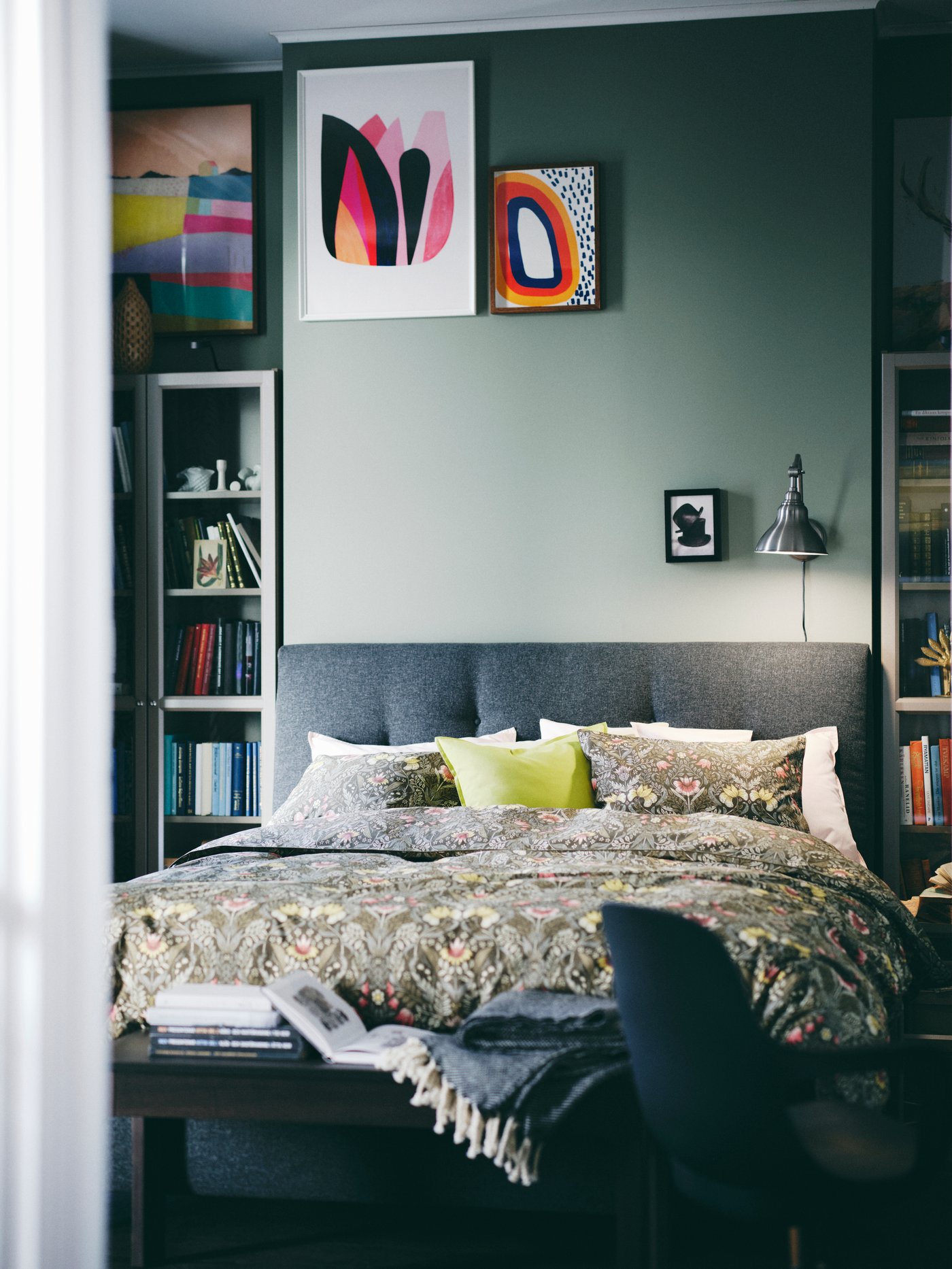 Dormitorio con cama de almacenaje tapizada en gris con detalles de botones clásicos, cubierta por una funda nórdica con 2 fundas de almohada.