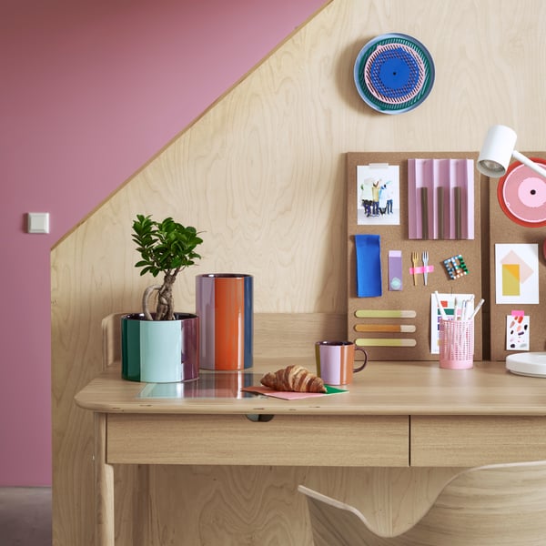 Wood desk in front of a staircase with planners, organizers and supplies on top.