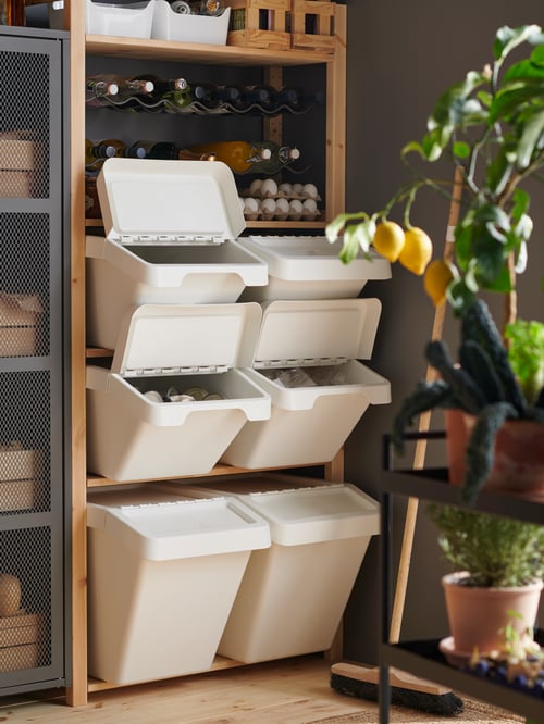 屋外の納屋にあるシェルフユニットに、ホワイトのプラスチック製のごみ箱がいくつか置いてあり、ごみを分別できるようになっている。
