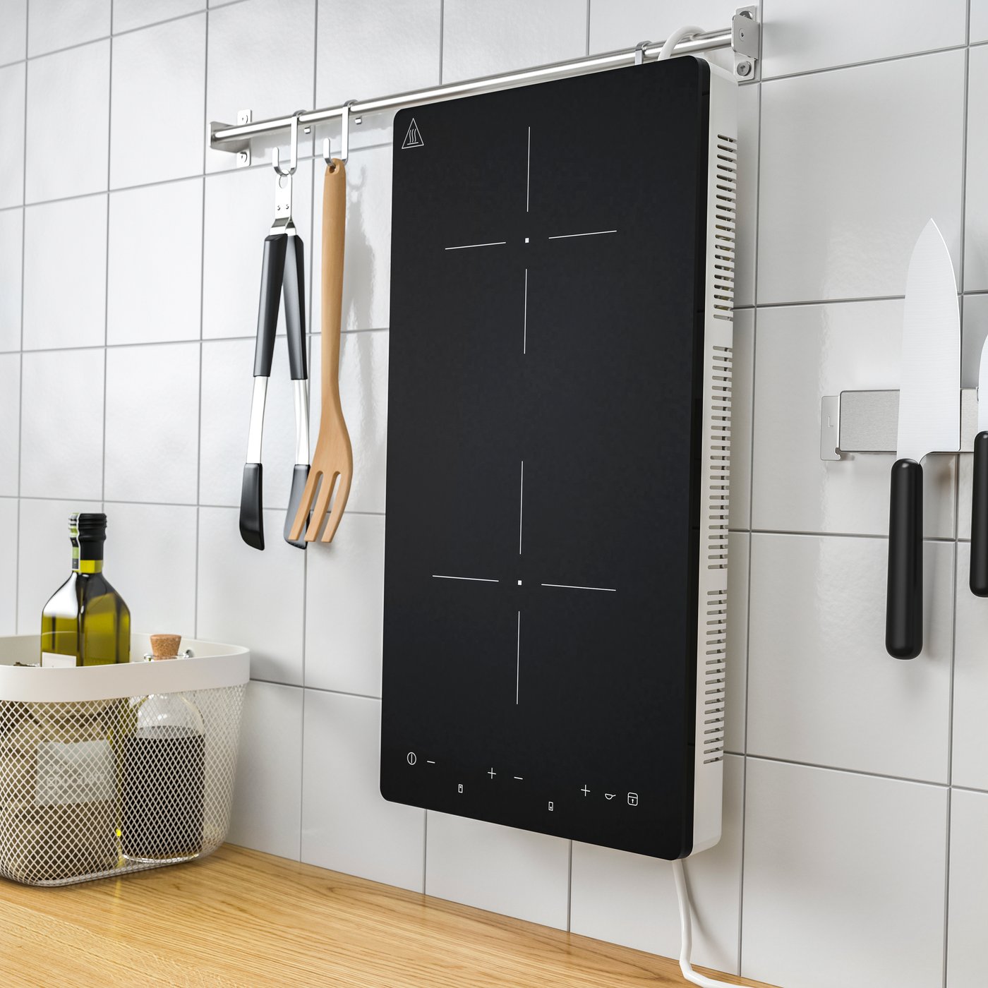 Piano cottura a induzione portatile TILLREDA bianco a 2 zone, appeso verticalmente alla parete piastrellata di una cucina.