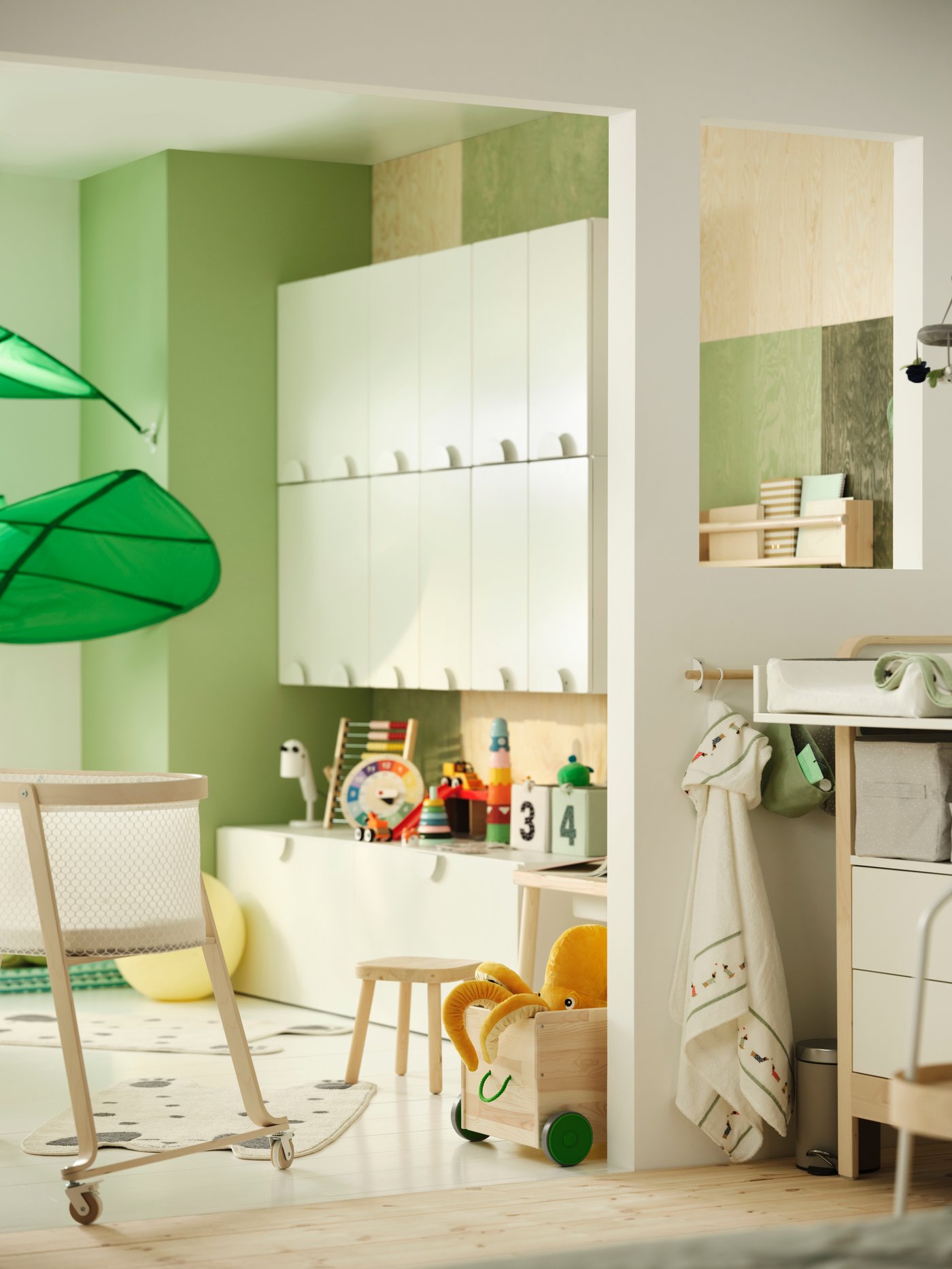 Es ist ein Kinderzimmer zu sehen, das zum Teil durch eine Wand geteilt wird. Auf einer Seite stehen SMÅSTAD Schränke mit Spielzeug. Auf der anderen befindet sich ein Wickelbereich.