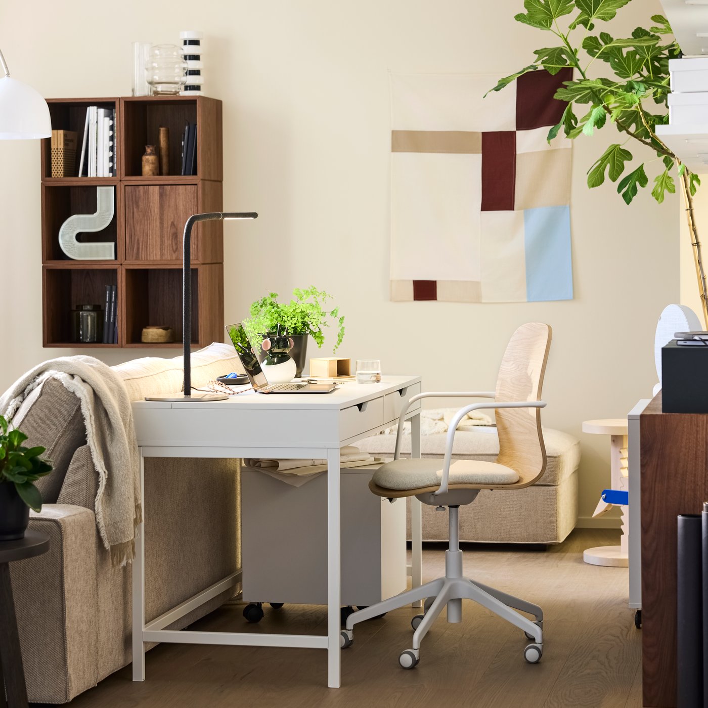 An ALEX desk with a drawer unit, in a workspace behind a sofa, paired with a SPELBREDD conference chair.
