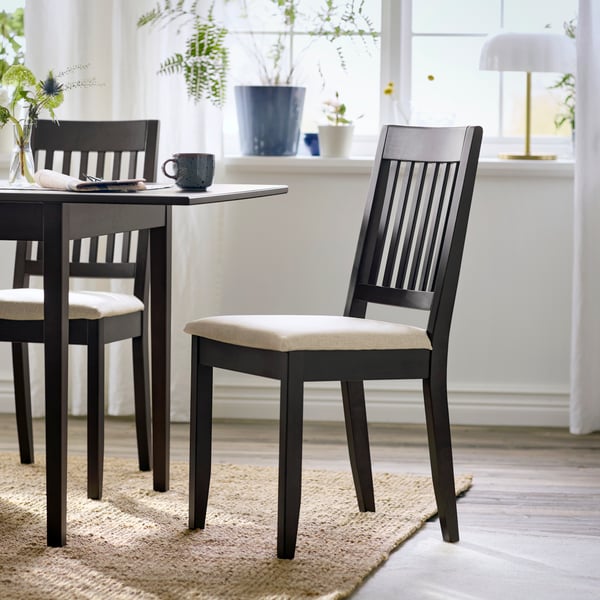 A dark brown NÄSINGE chair with light beige cushion, set beside a dining table in a bright, airy room.