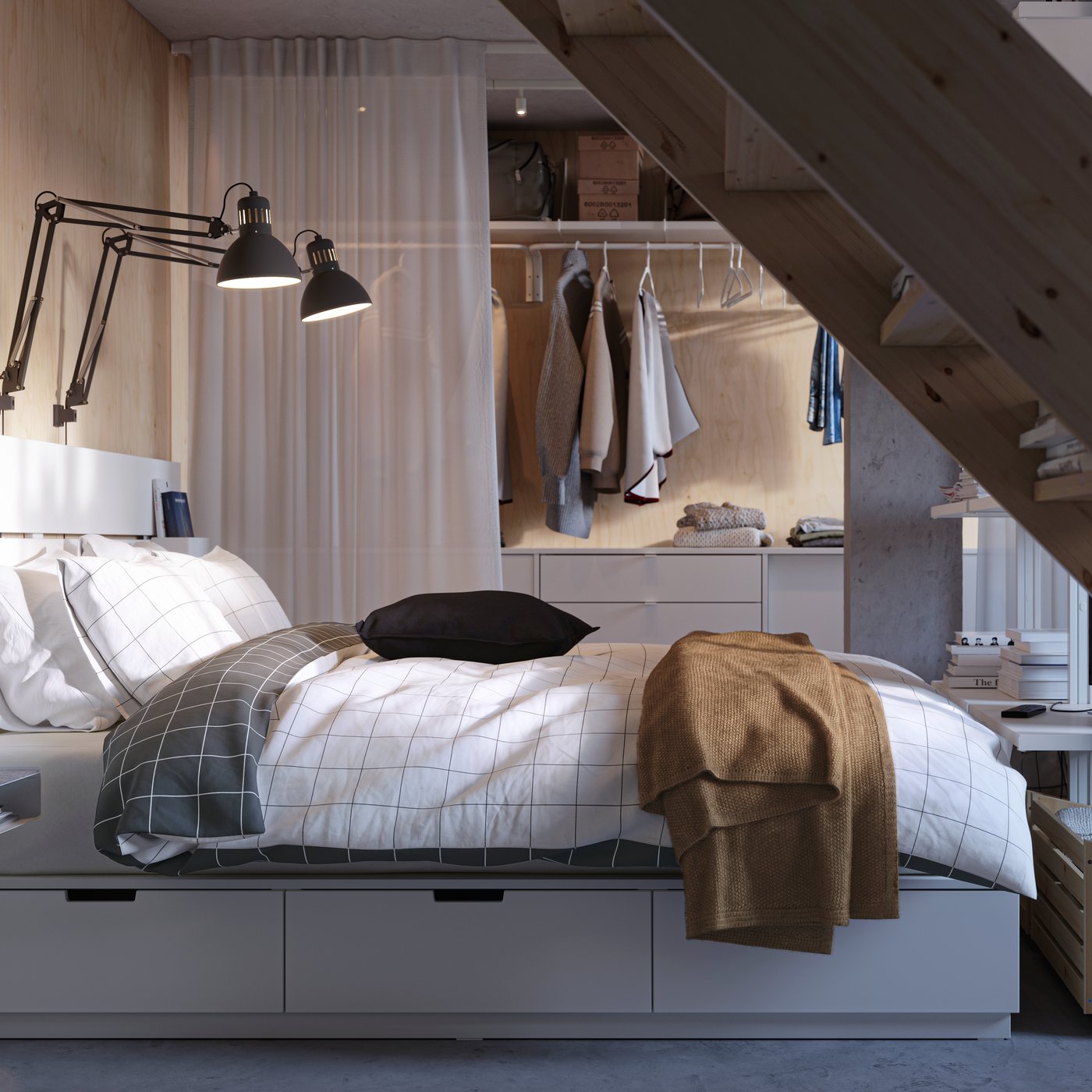 Un letto NORDLI bianco con cassetti e testiera, preparato con biancheria da letto VITKLÖVER, davanti a una combinazione di guardaroba ELVARLI.