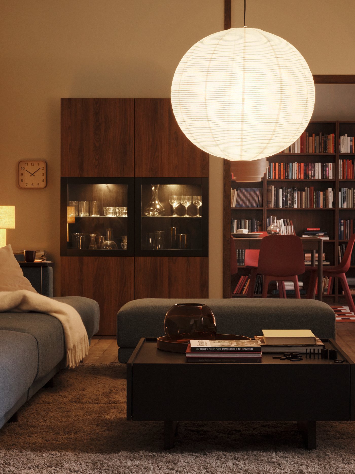 A lamp with a GULLSUDARE pendant lampshade hangs in a living room with a STOCKHOLM 2025 table lamp in one corner.