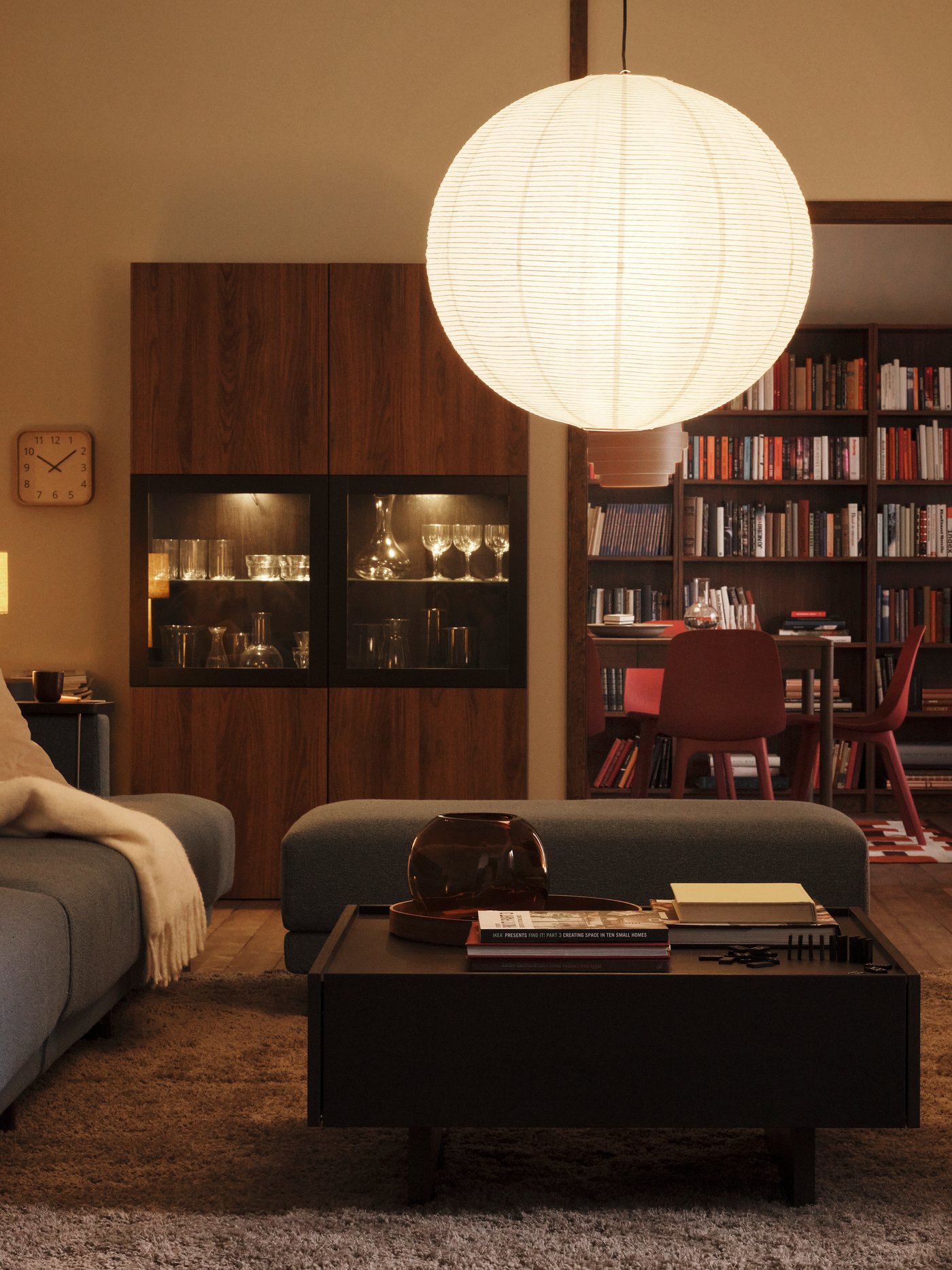A lamp with a GULLSUDARE pendant lampshade hangs in a living room with a STOCKHOLM 2025 table lamp in one corner.