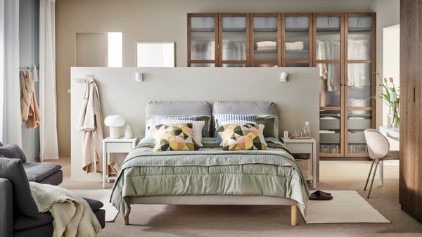 A calm bedroom with a grey GLADSTAD bed, a wooden desk, a dynamic grey wardrobe and round lamps hanging from the ceiling.