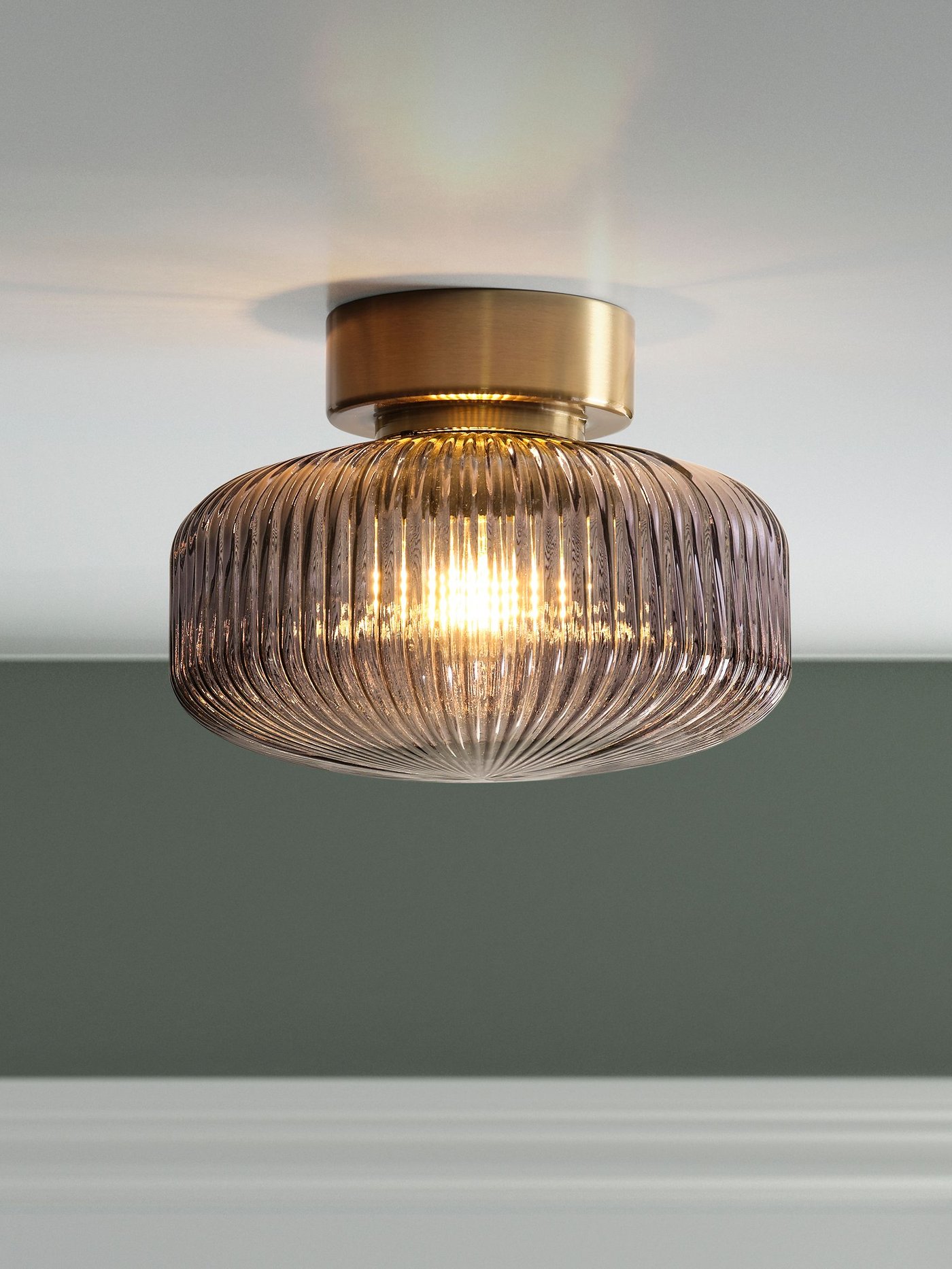 مصباح سقف SOLKLINT نحاسي / زجاجي شفاف باللون الرمادي مثبت في السقف في غرفة بتصميم بالأبيض والأخضر.