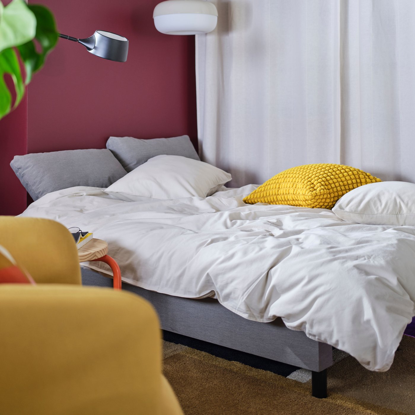 Sofá cama ÄLVDALEN IKEA de color gris con un plumón blanco y almohadas encima