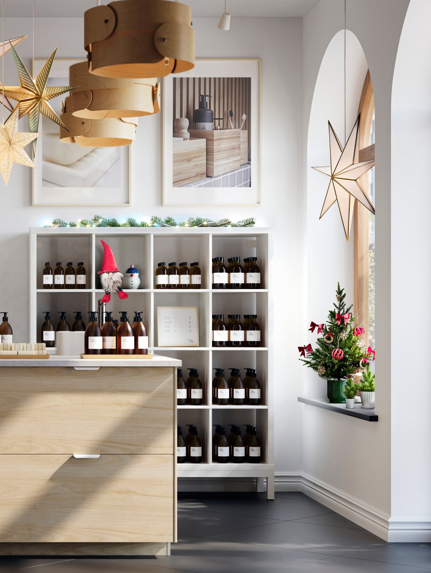 Interno di un negozio luminoso e spazioso il cui punto focale è una grande isola cucina con frontali per cassetti ASKERSUND effetto frassino chiaro. Decorato con luci a LED STRÅLA e decorazioni VINTERFINT.