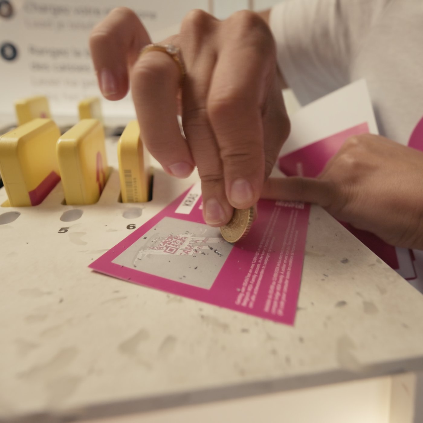 Een hand krast een vakje open op een roze IKEA-kaart met een muntstuk bij een promotionele actie of wedstrijd in de winkel.