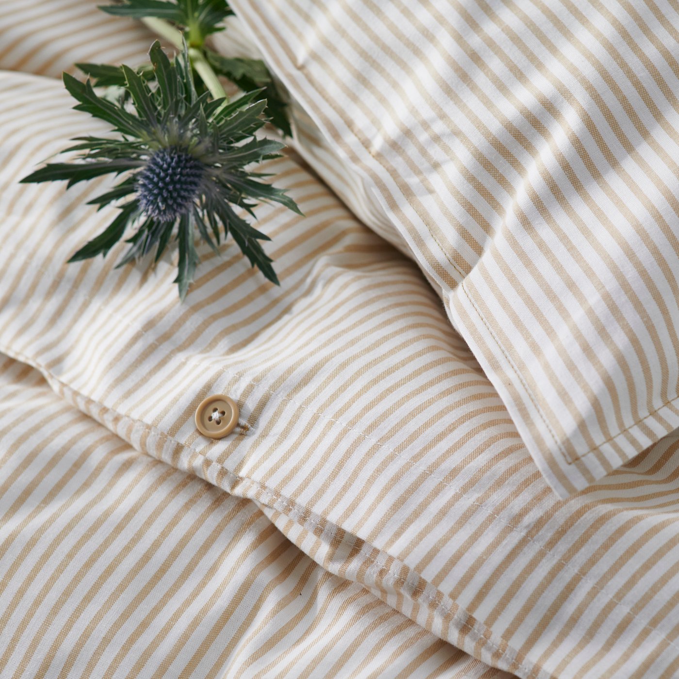 Lähikuva valkobeigeraidallisesta SOLFIBBLA-pussilakanasta ja -tyynyliinasta.