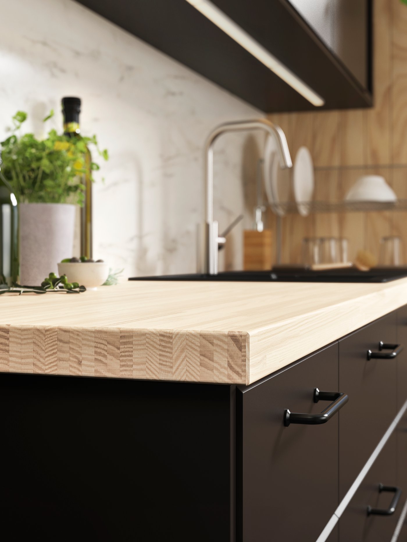 Cocina con un armario con tiradores negros y una encimera beige. También hay un grifo desenfocado.