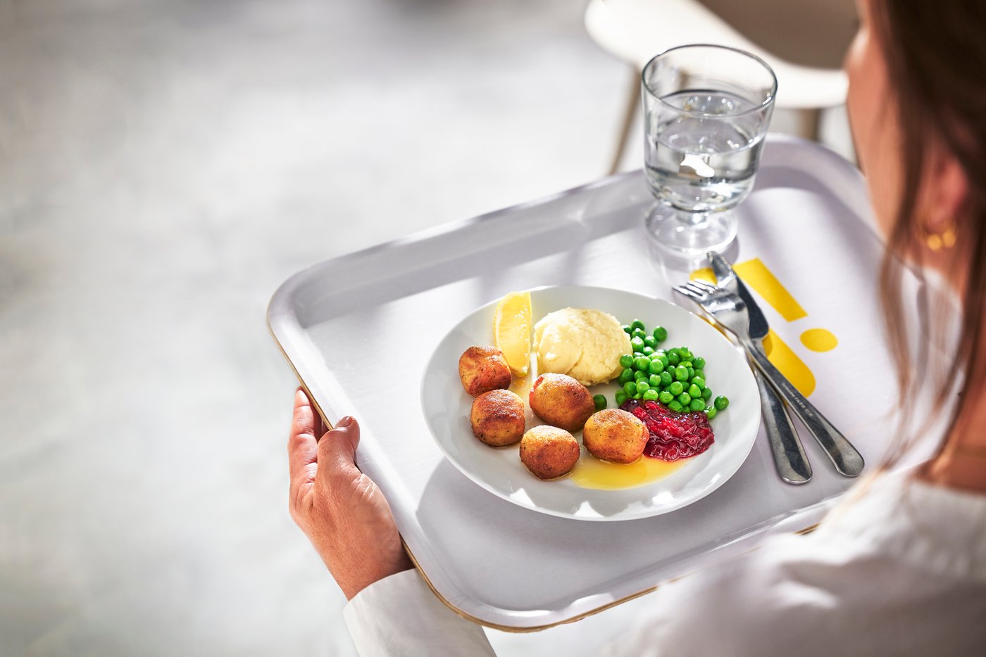 Krožnik s kroglicami, krompirjem in grahom na pladnju