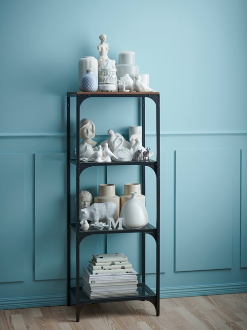 Living cu unitate de rafturi, vaze de diferite forme și dimensiuni, materiale textile pliate, perete albastru deschis, obiecte decorative.