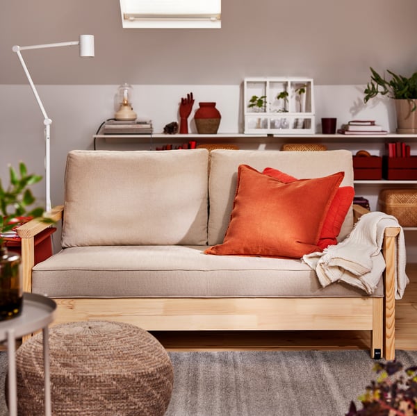 A TORNSBORG sofa-bed with a throw and extra cushions on it, including one with a red-brown DYTÅG cushion cover.