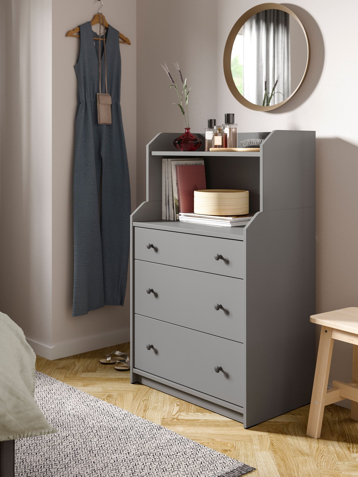 En grå byrå är placerad mot en vägg i ett sovrum.